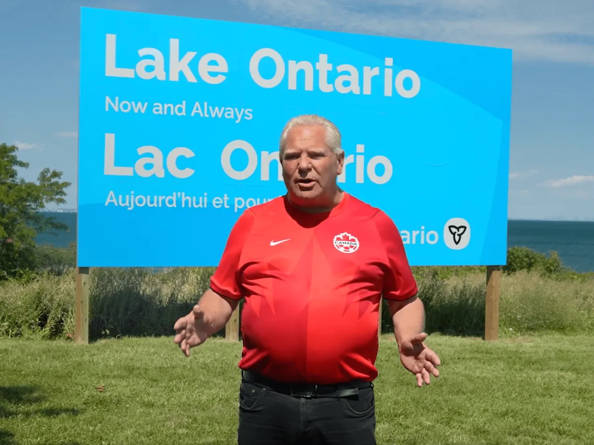 Doug Ford stands by a sign reading Lake Ontario on Hamilton’s waterfront