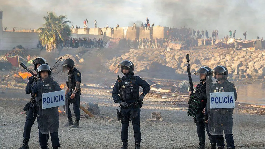 Police and protesters during unrest in Ceuta after a migrant influx