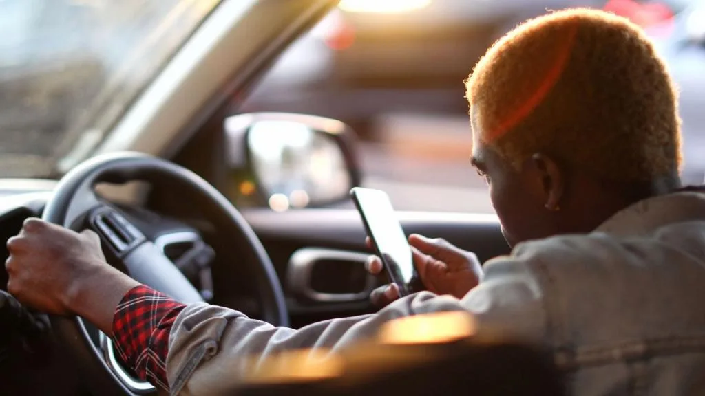 Uber logo on a phone screen with African city traffic in the background
