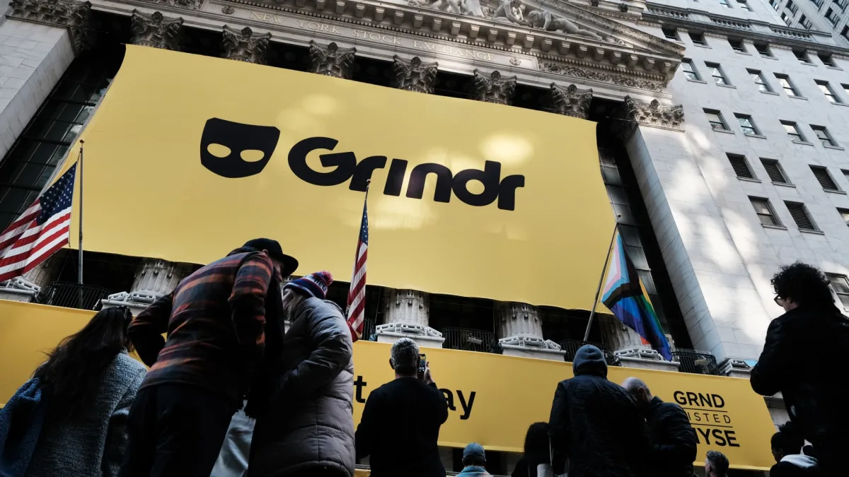 Grindr app on a phone with PurposeMed and Freddie acquisition news