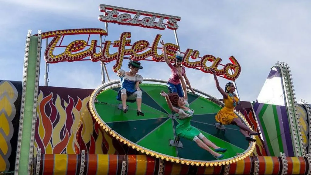 Visitantes del Oktoberfest en Múnich junto al Teufelsrad con carteles de advertencia