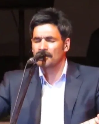 Mikrofon karşısında sahne alan şarkıcı, söz yazarı, besteci ve sunucu Uğur Işılak